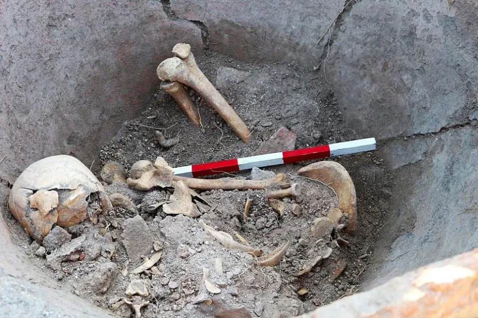 Širší pohled na kosterní pozůstatky uvnitř keramické římské nádoby, tzv. dolia, v níž byly nalezeny; pozůstatky seděly v pozici, která pravděpodobně kdysi sloužila jako obranný přikrčený postoj, a v ruce svíraly železný nůž. Zdroj: Archaeologia Bulgarica
